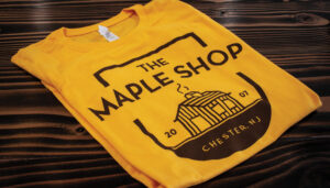 The Maple Shop logo on a yellow shirt