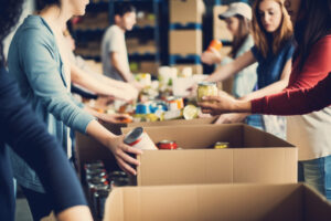 Group of younger people volunteering at a soup kitchen collecting food dcans